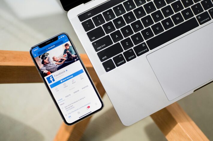 facebook app op smartphone naast macbook